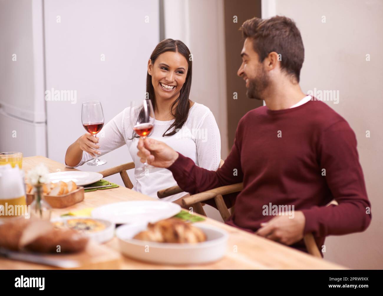 Lets toast to the food on our table. A happy couple enjoying a family meal around the table. Stock Photo