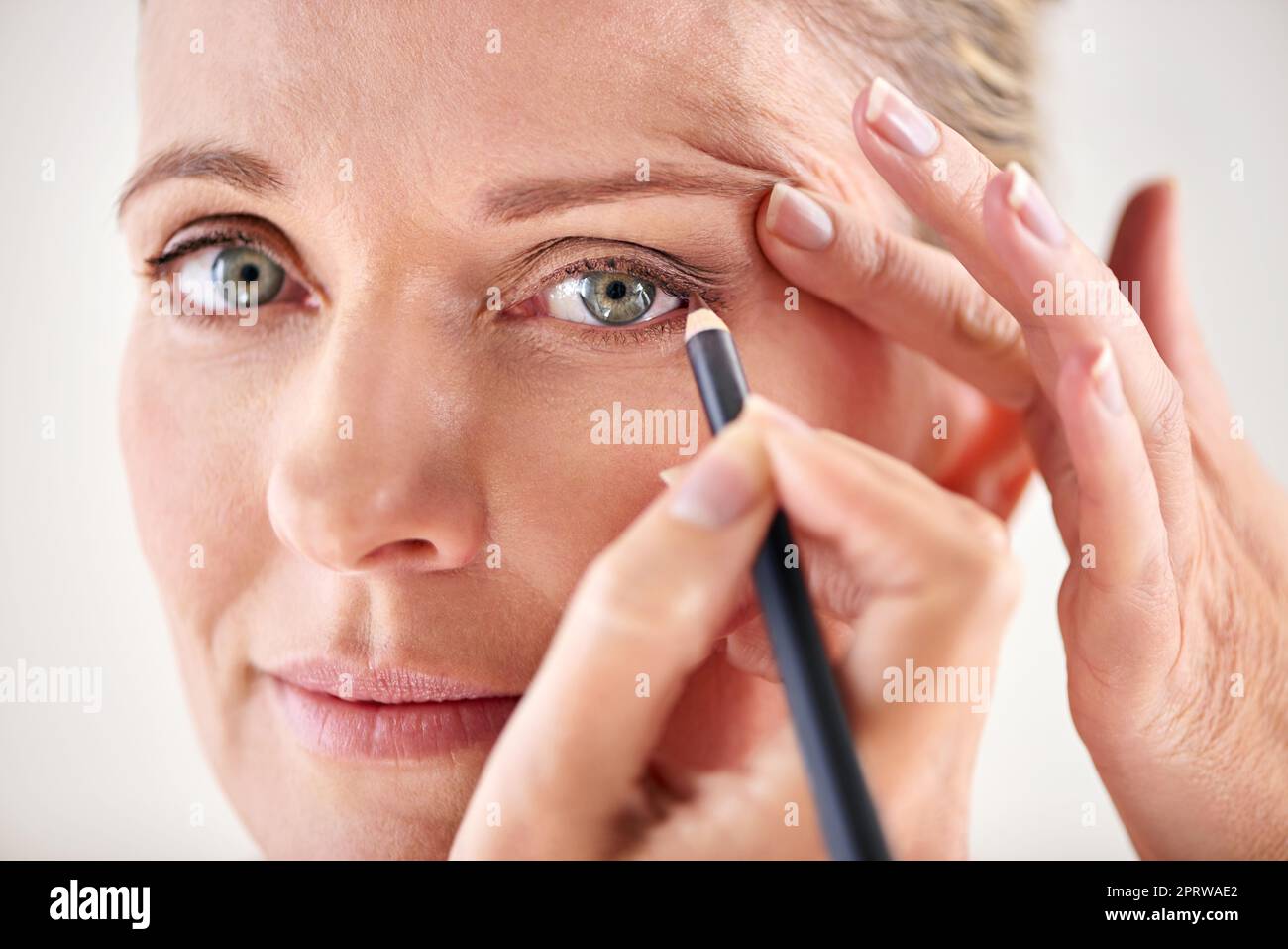 Making her best features stand out. Cropped studio shot of a mature woman applying eyeliner. Stock Photo
