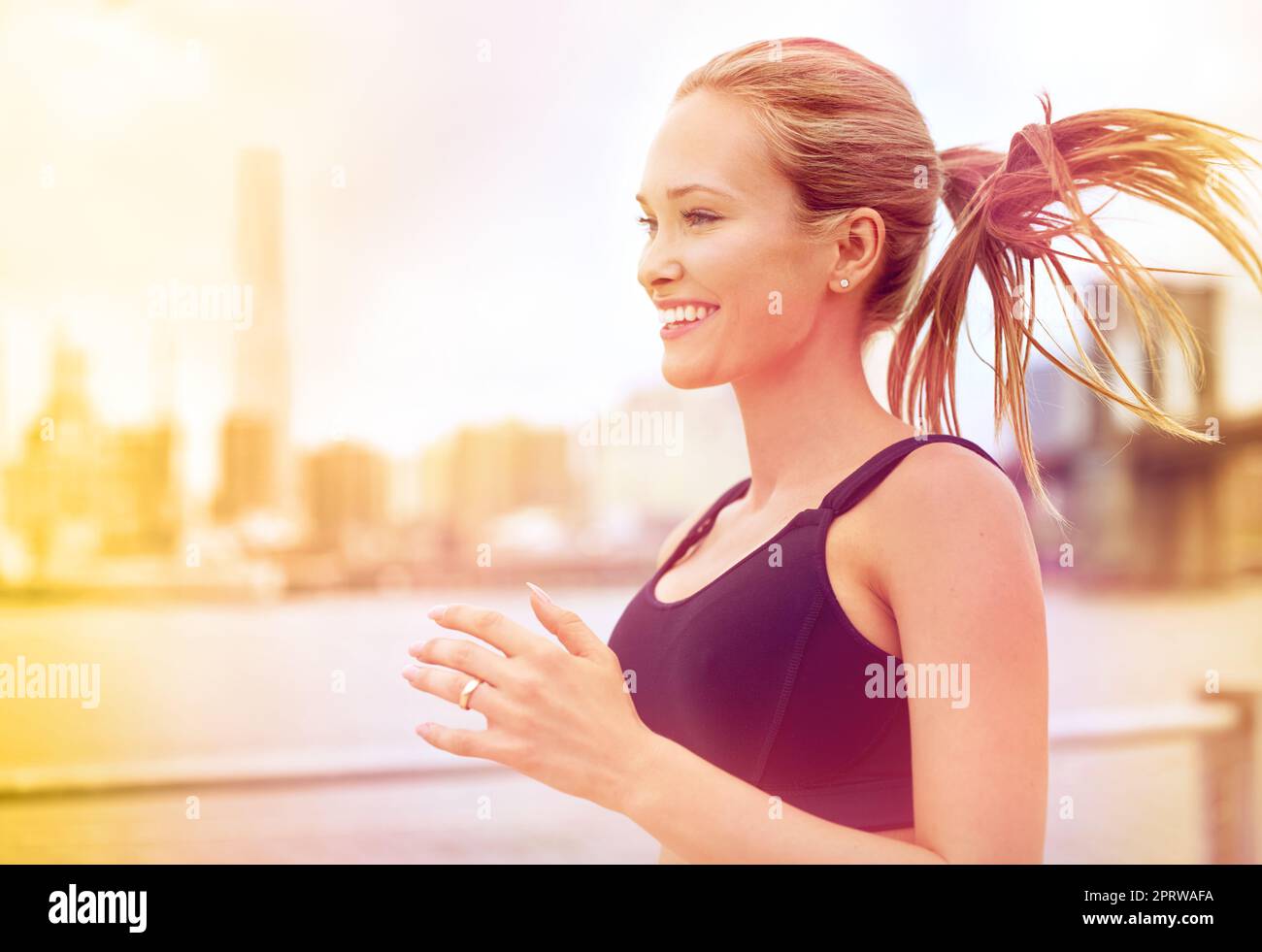 Theme is sport and health. Beautiful young caucasian woman with big breasts  athlete runner stands resting on running stadium, running track with bottle  in hands drinking water in short shorts Stock Photo