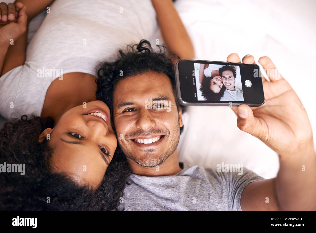 Capturing the moment. A cute couple taking a selfie on the bed Stock