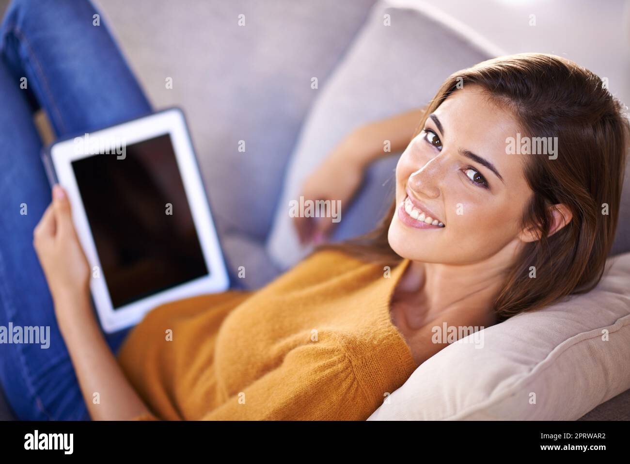 Getting in some sofa time. a gorgeous young woman using a digital tablet indoors. Stock Photo