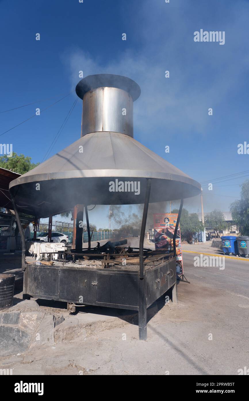 A woodfired parrilla or grill being fired up to roast chivito, or goat, at the Difunta Correa
