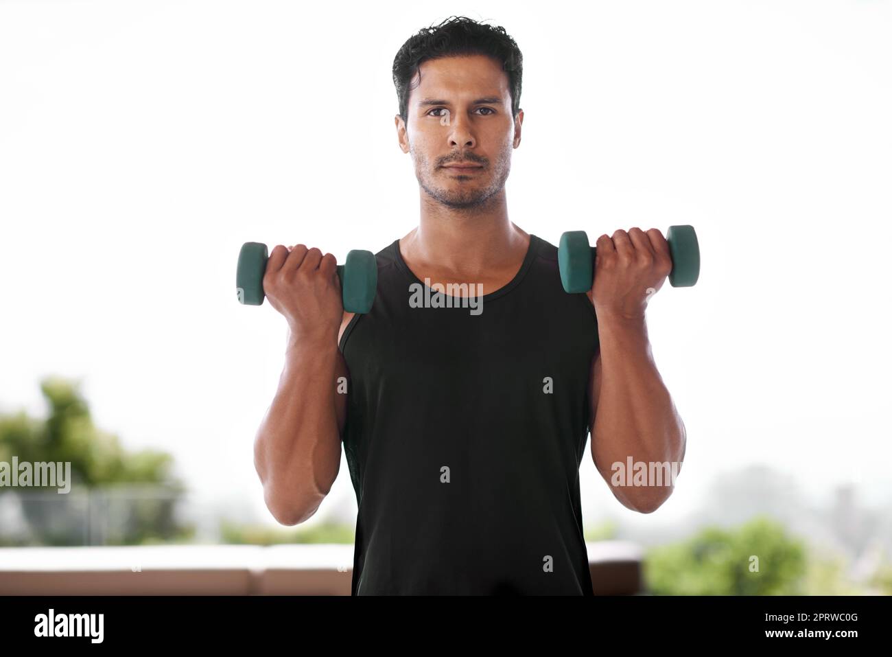 Let me show you how its done. Portrait of a handsome man exercising with dumbbells. Stock Photo
