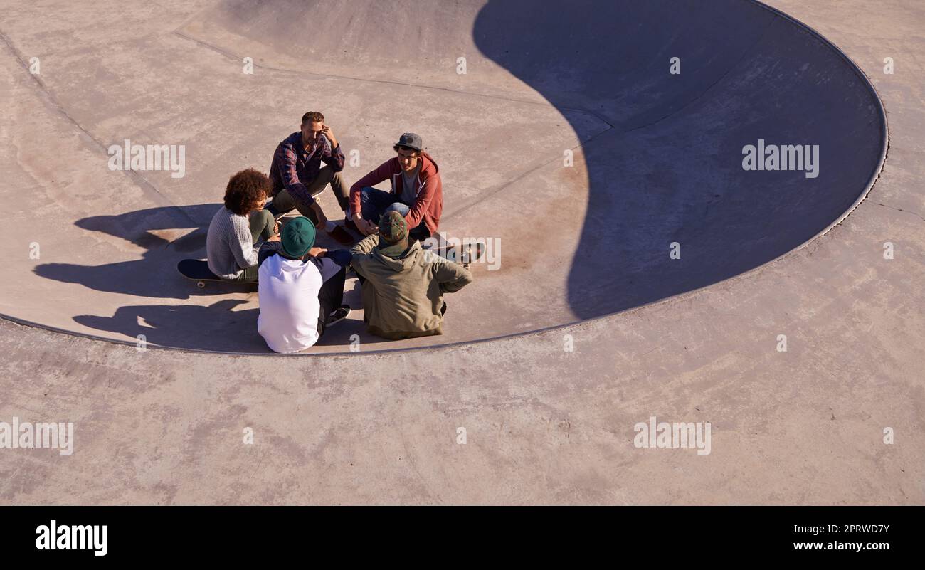 In the middle of what they love. a group of friends hanging out in the sun at a skate park. Stock Photo