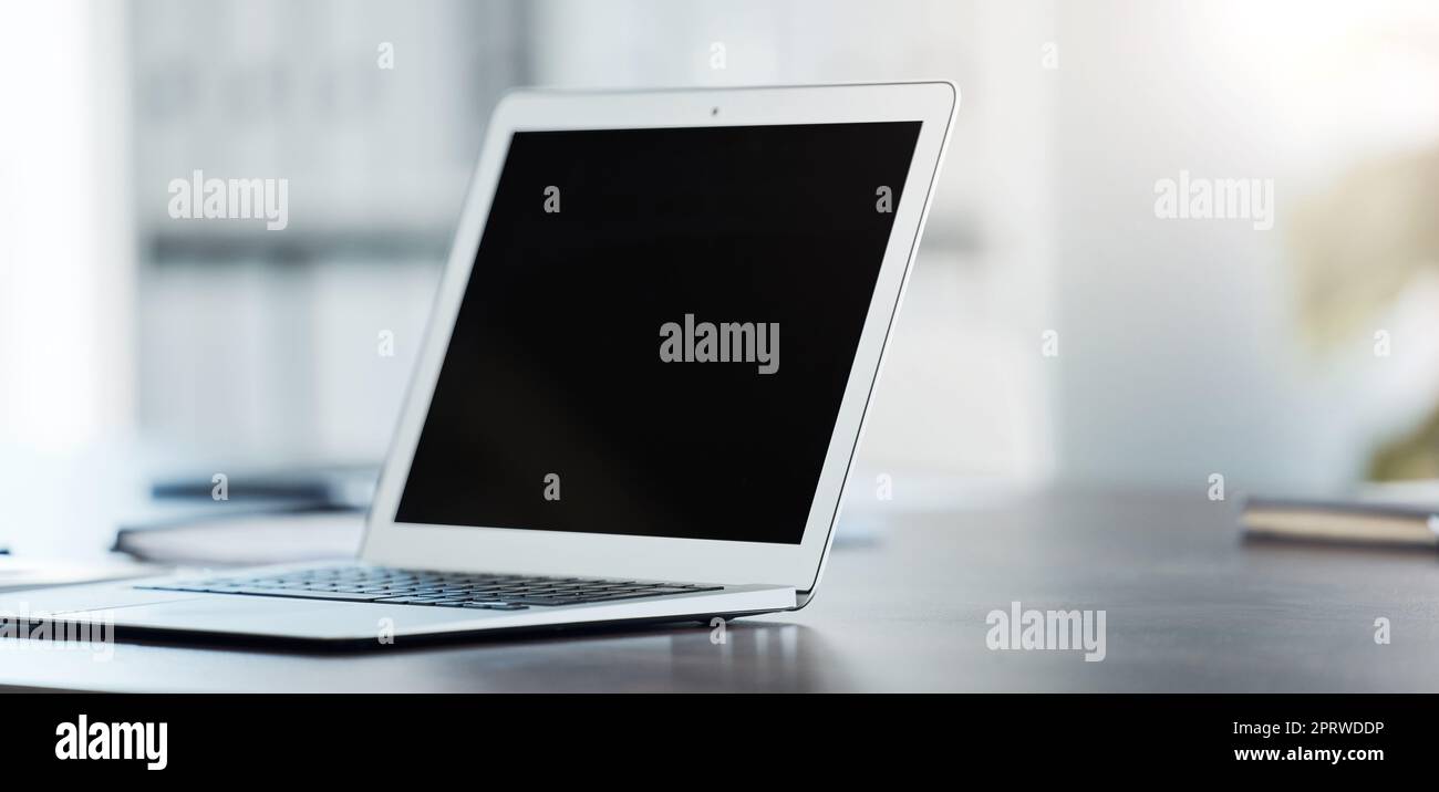 Digital, laptop and black screen mock up on table surface in office building for marketing, design and frame. Desktop, monitor and online with creative mockup on empty or blank pc display on desk Stock Photo