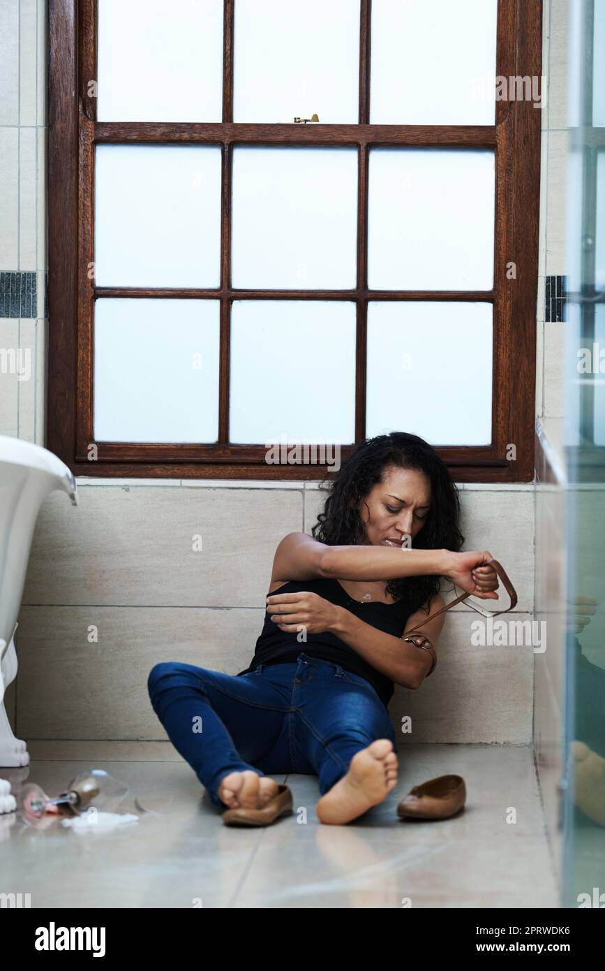 Going through the ritual. a drug addict preparing to inject on the bathroom floor. Stock Photo