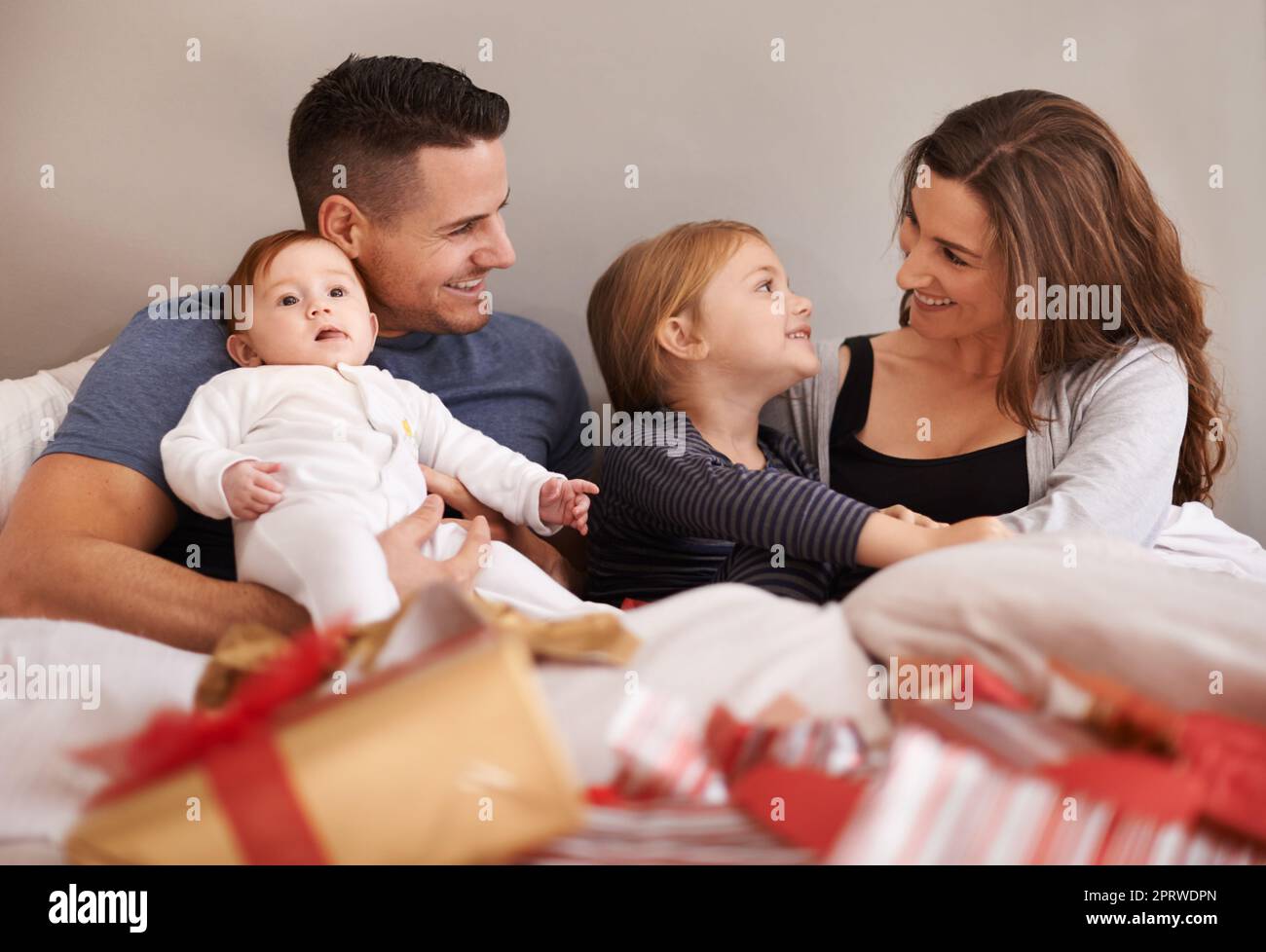Did you like your presents. an affectionate young family lying in bed and exchanging gifts. Stock Photo