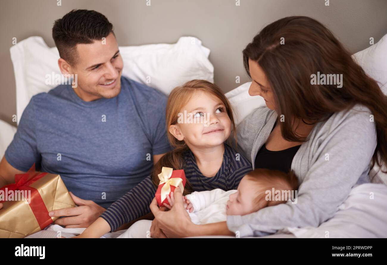 Its someones birthday. an affectionate young family lying in bed and exchanging gifts. Stock Photo