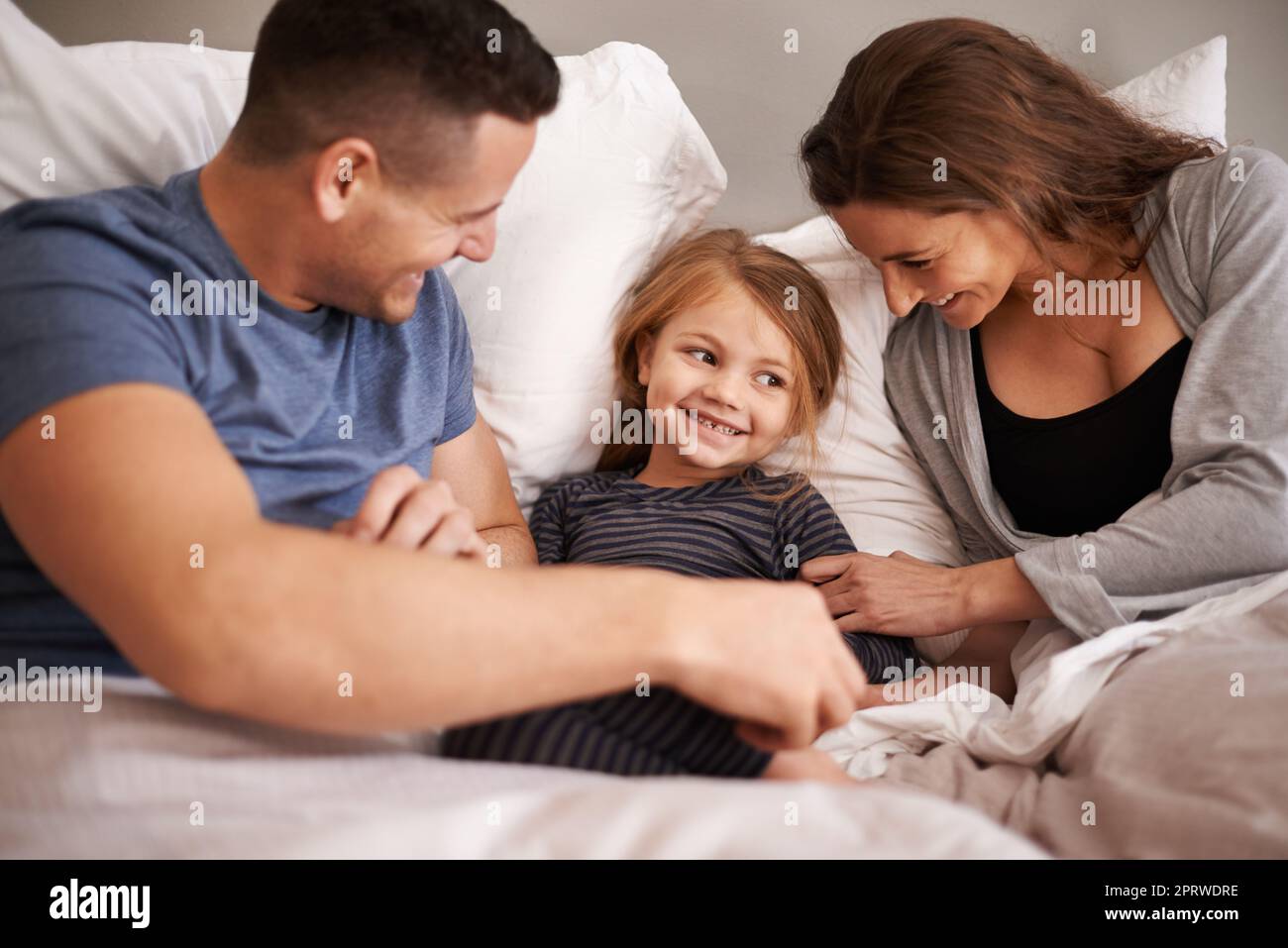 Playful parents. an affectionate young family lying in bed together. Stock Photo