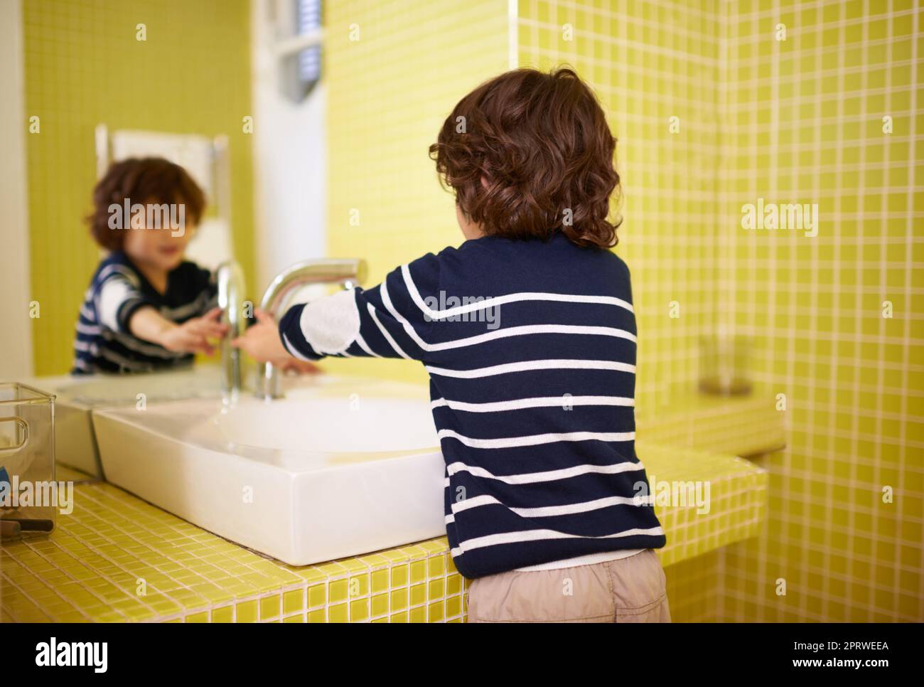 Washing up before dinner. A cute little boy washing his hands in the bathroom basin. Stock Photo