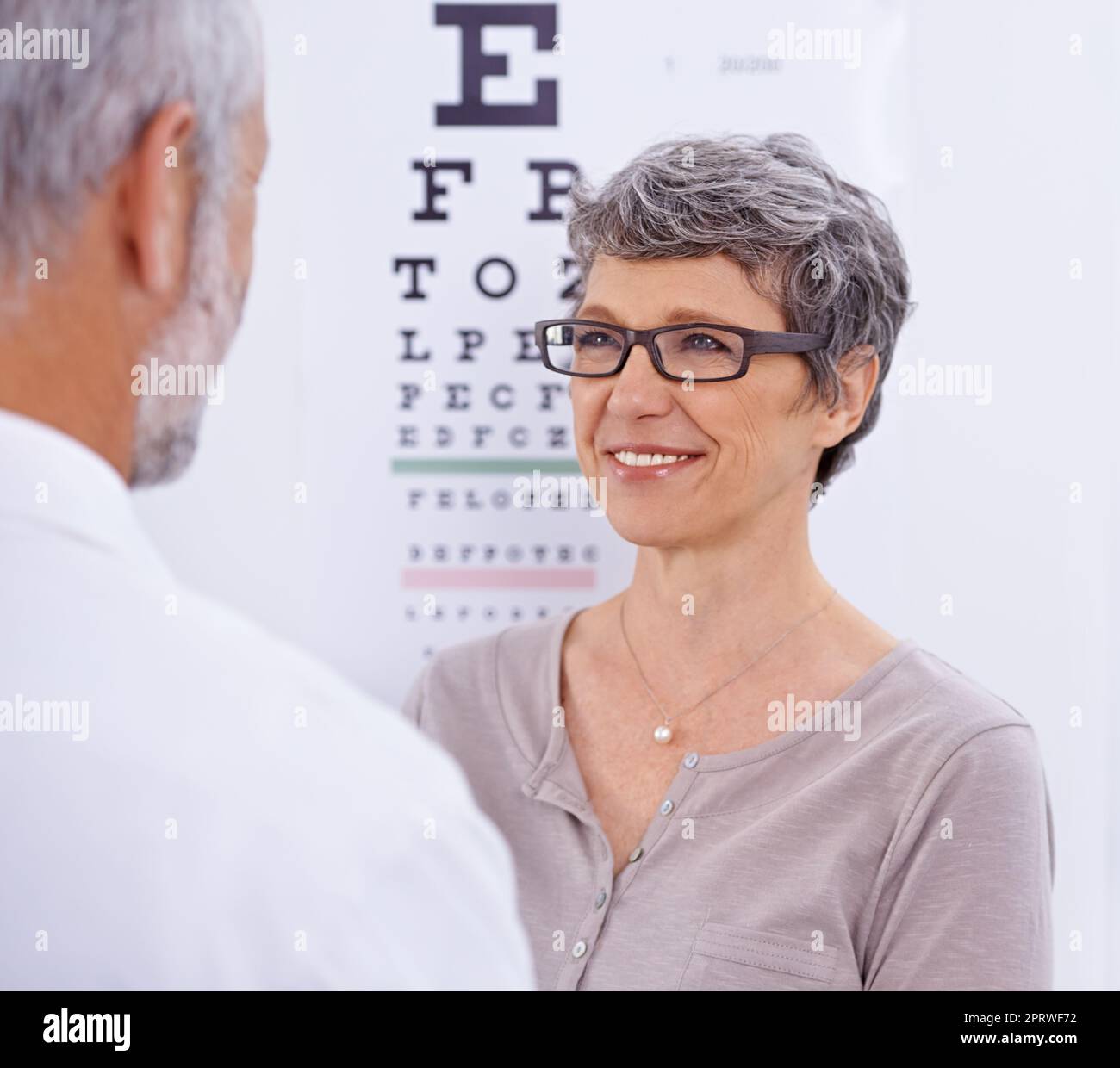 Can you see me now. a mature woman wearing glasses facing an optometrist. Stock Photo