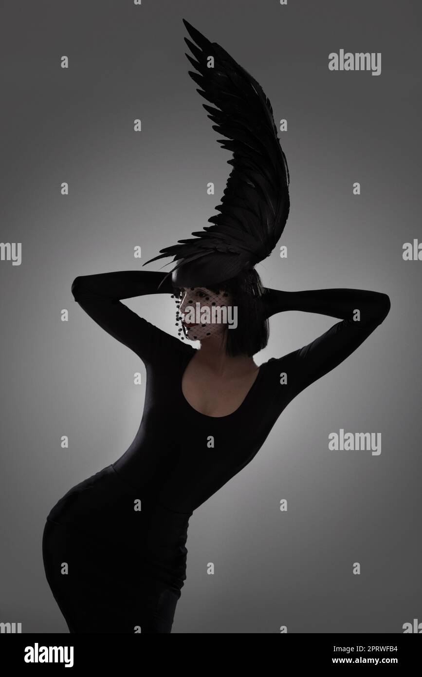 Beautiful plumage. a young woman in a wing-shaped headpiece standing in a studio. Stock Photo