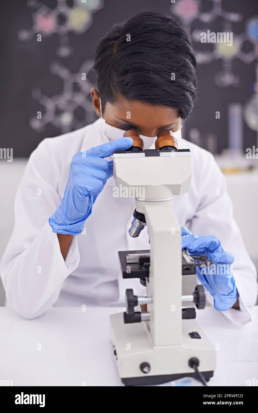 Careful analysis and observation. A young scientist using a microscope in her lab. Stock Photo