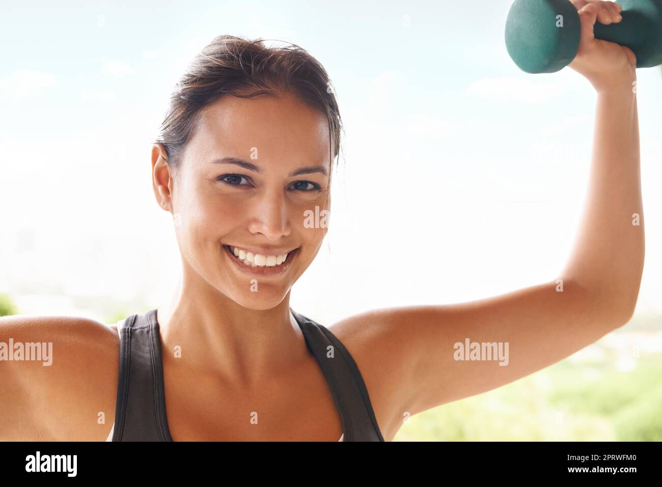 Making her muscles smile. Portrait of a sporty young woman working out with dumbbells. Stock Photo