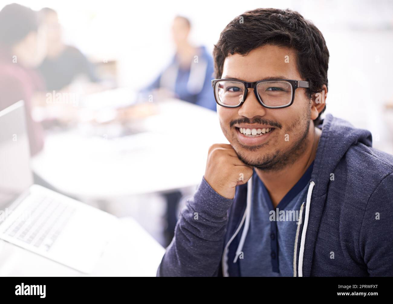 Nothing is impossible when youre a a programmer. Portrait of a happy young man working on his laptop in an office. Stock Photo