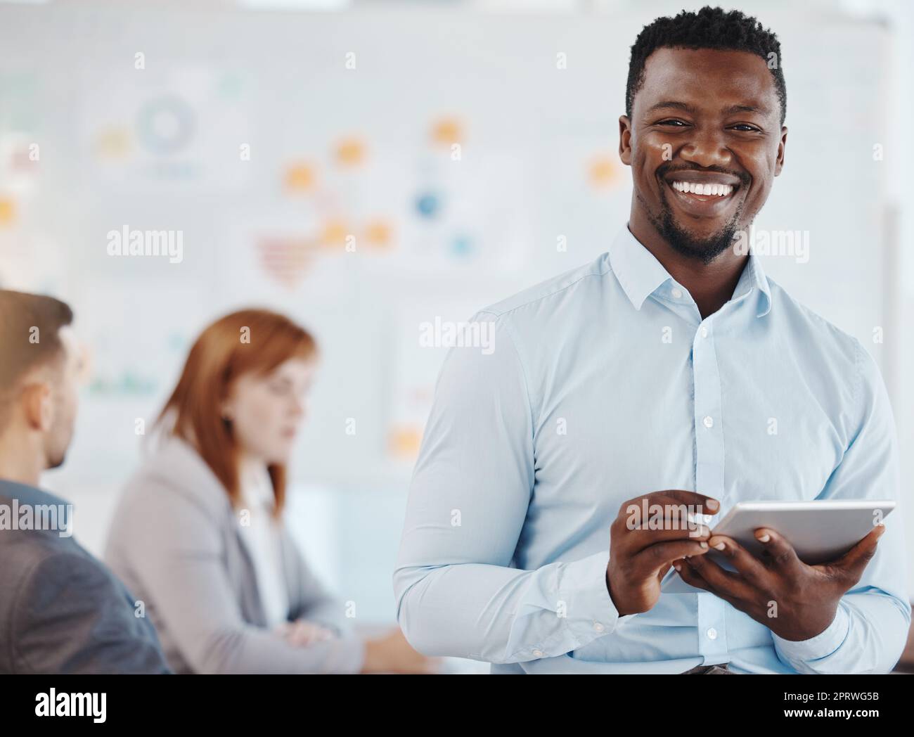 Leadership, motivation and business man planning on digital tablet and looking proud in a group meeting. Strategy, vision and marketing by black man portrait leading a design team mission discussion Stock Photo