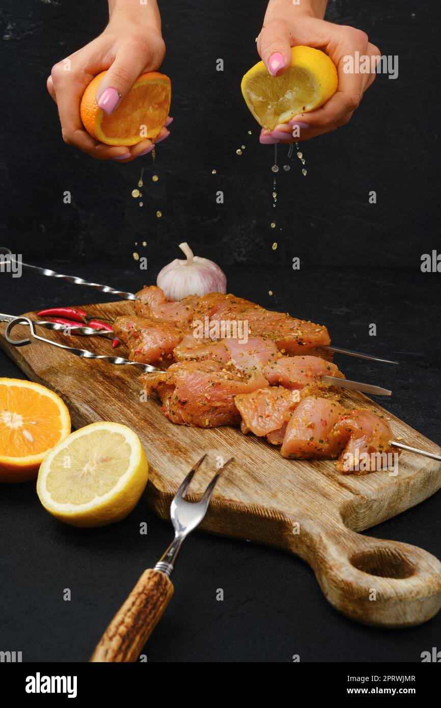 Pouring orange and lemon juice on skewers with raw turkey meat Stock