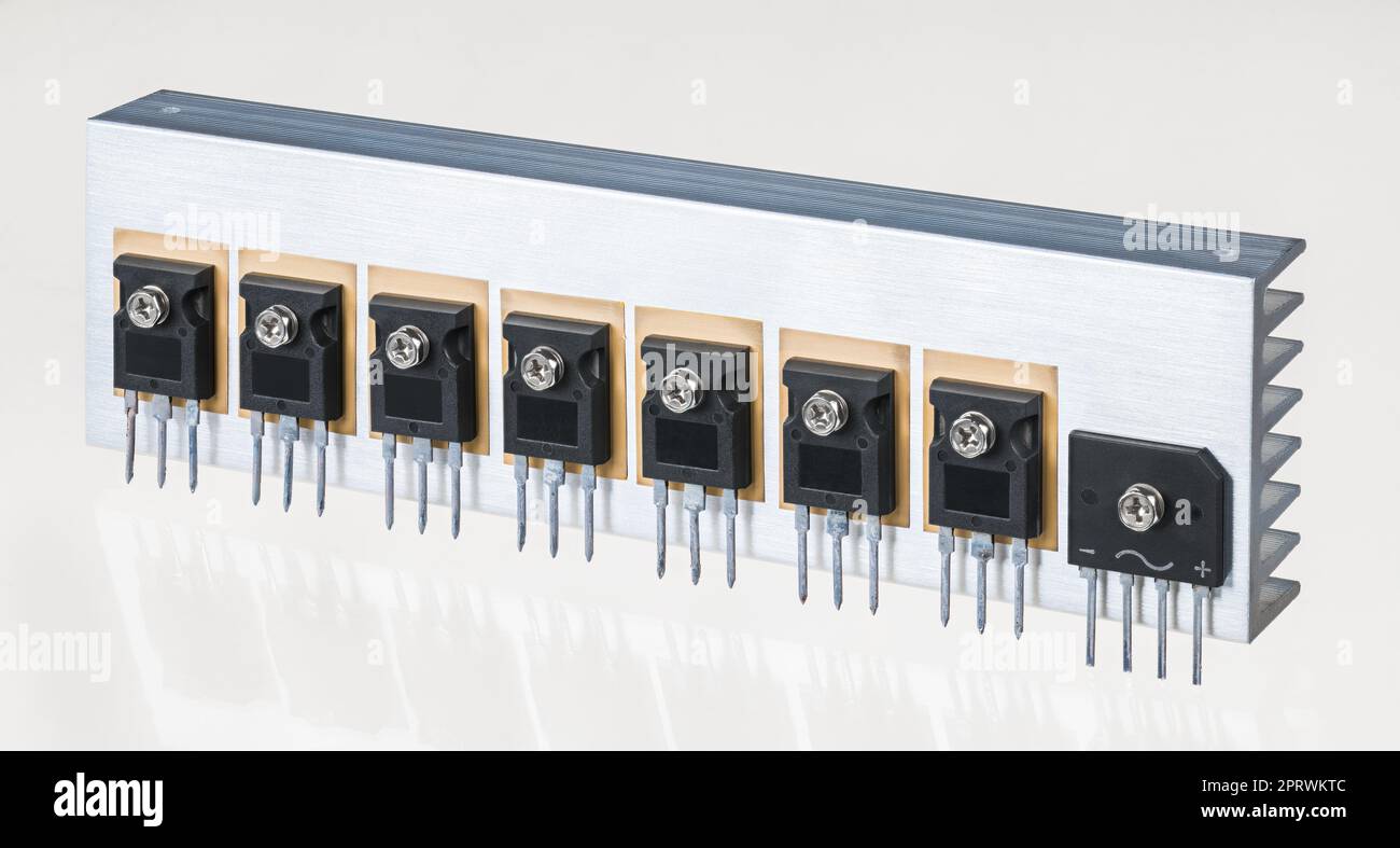 Electrical components on aluminum heat sink of switch-mode power supply on a white background. Insulated gate bipolar transistors and bridge rectifier Stock Photo