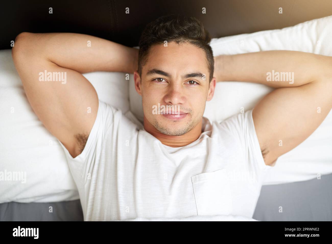 Just lay back and relax. a handsome young man lying in bed Stock Photo