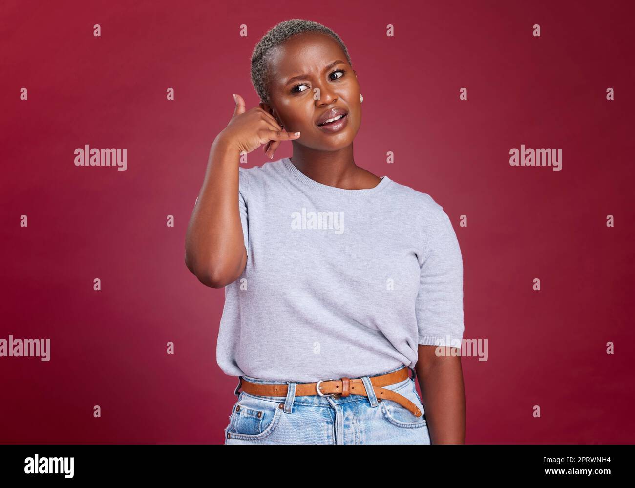 Black woman, annoyed and hand phone call sign by studio background for question, communication or network. Model, woman and call me symbol with frown Stock Photo