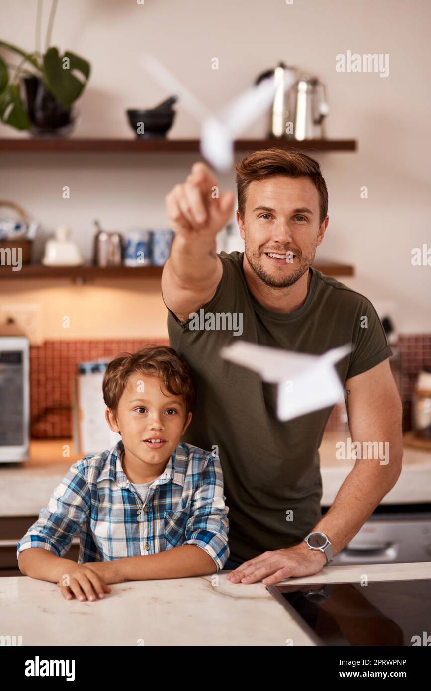 Lets see how high our planes can go. a man and his young son playing with paper planes at home. Stock Photo