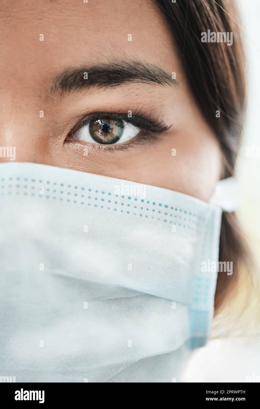 I am because we are. Closeup shot of a womans eye while wearing a mask on her face. Stock Photo