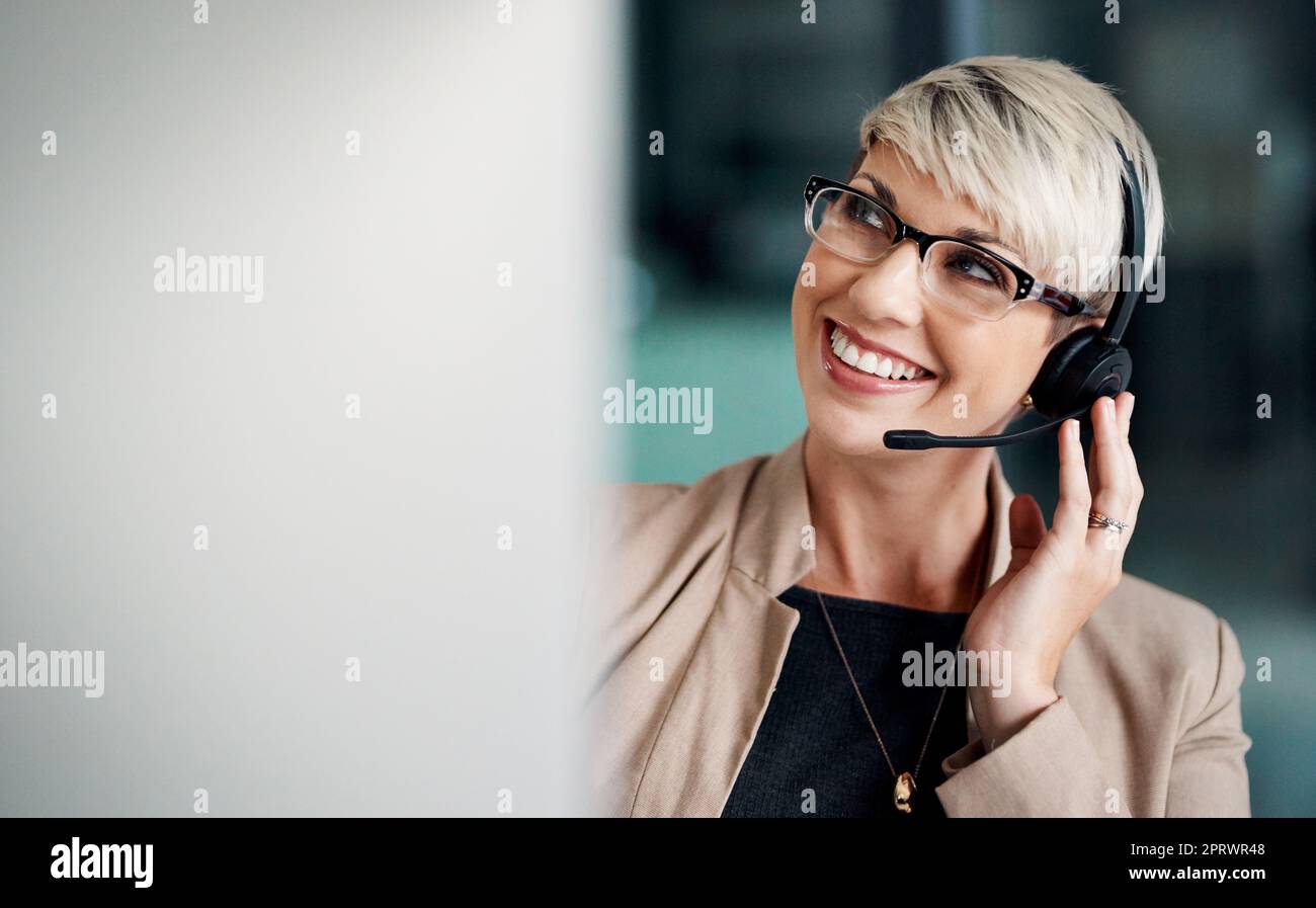 Keeping the line of communication open for customers. a young businesswoman wearing a headset while working on a computer in an office. Stock Photo