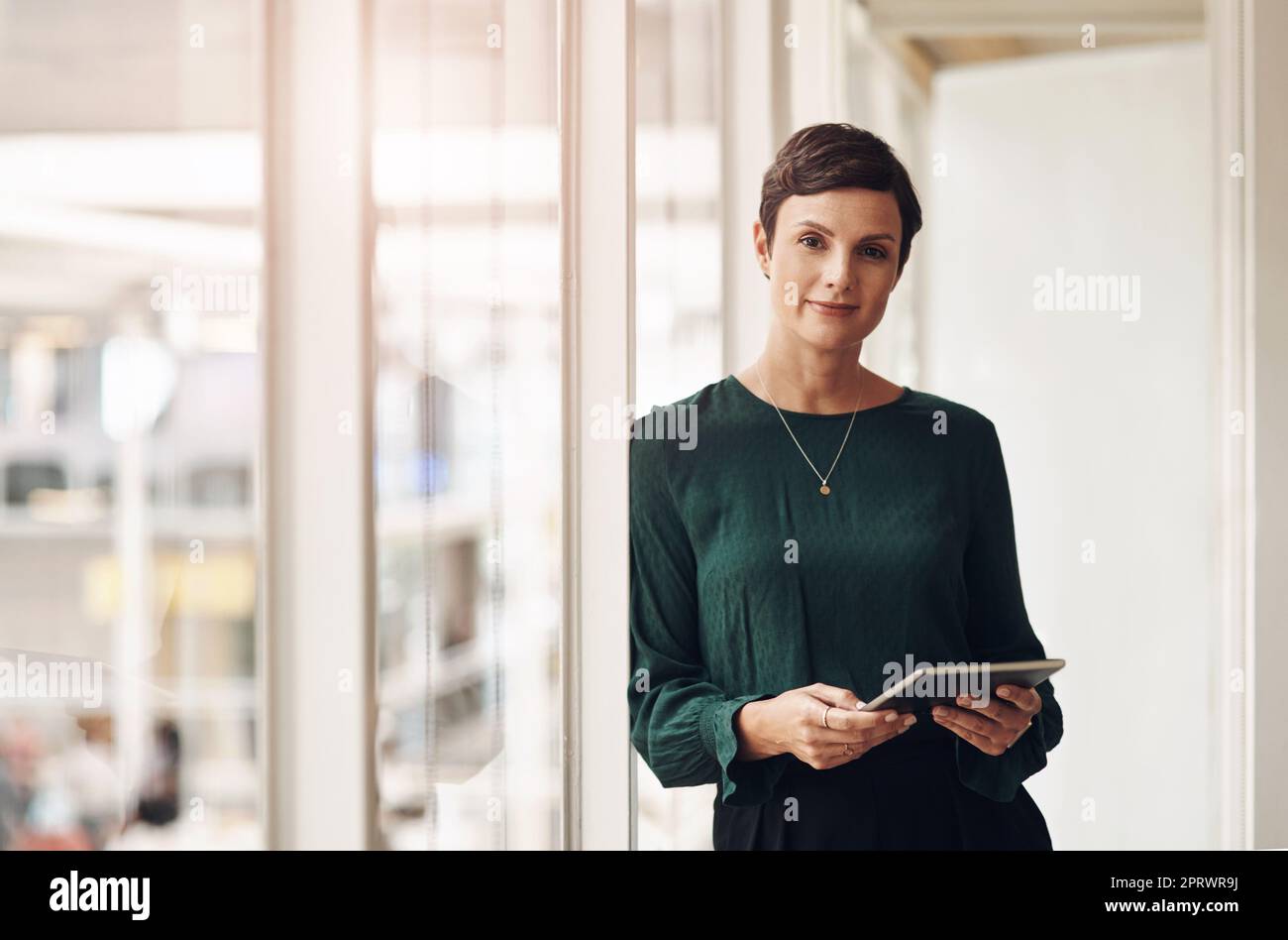 Technology is a businesswomans best friend. Cropped portrait of an attractive young businesswoman using her tablet while standing in the office. Stock Photo