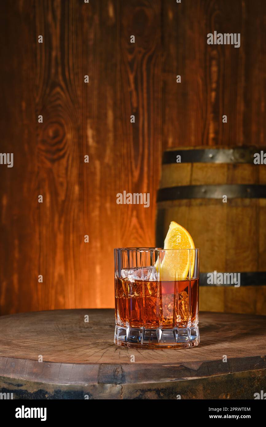 Cocktail with blended malt scotch whisky and orange bitter with a barrel on background Stock