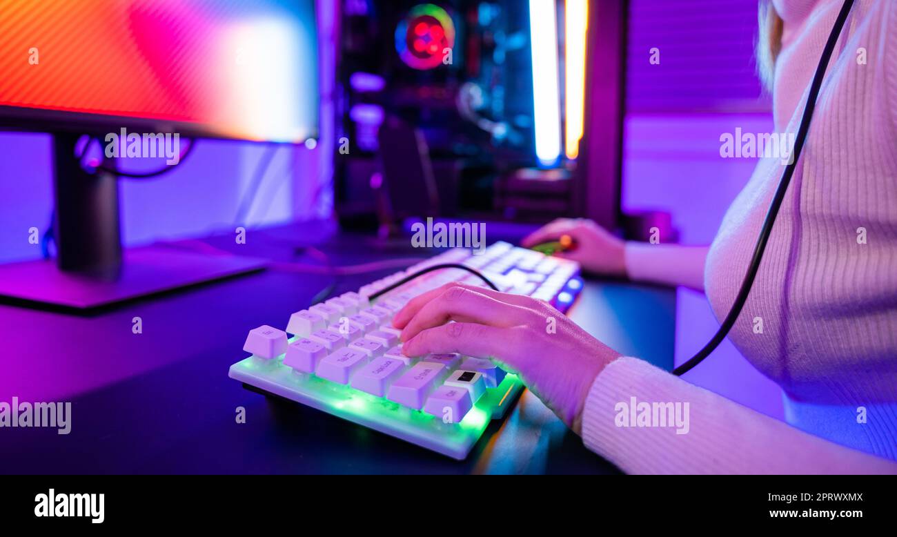Close up gamer hands actively pushing buttons with colorful neon LED lights Stock Photo