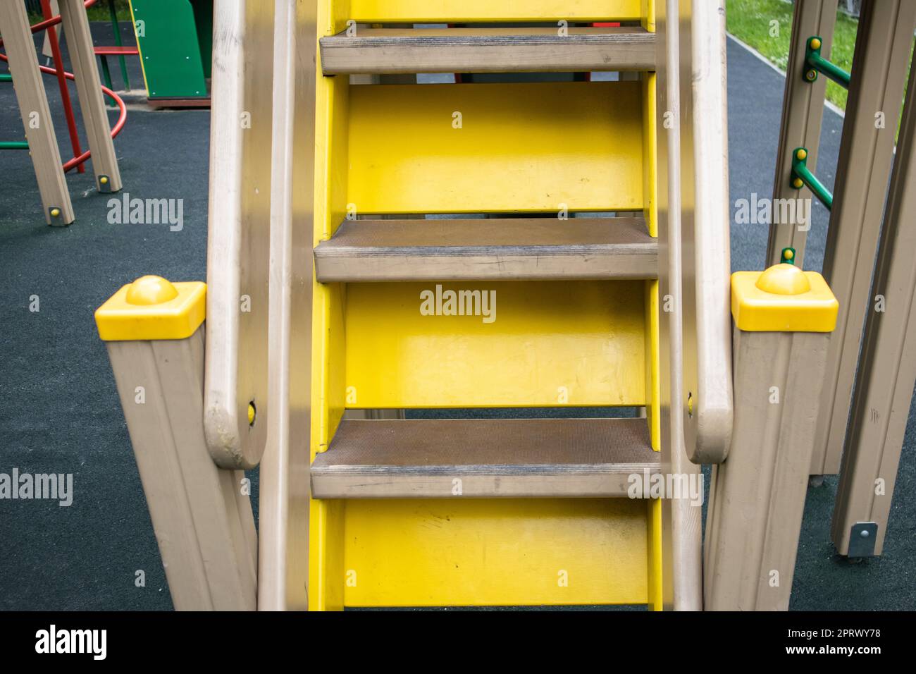 Close-up of wooden steps on an empty yellow staircase on an outdoor playground, a safe play area for children Stock Photo