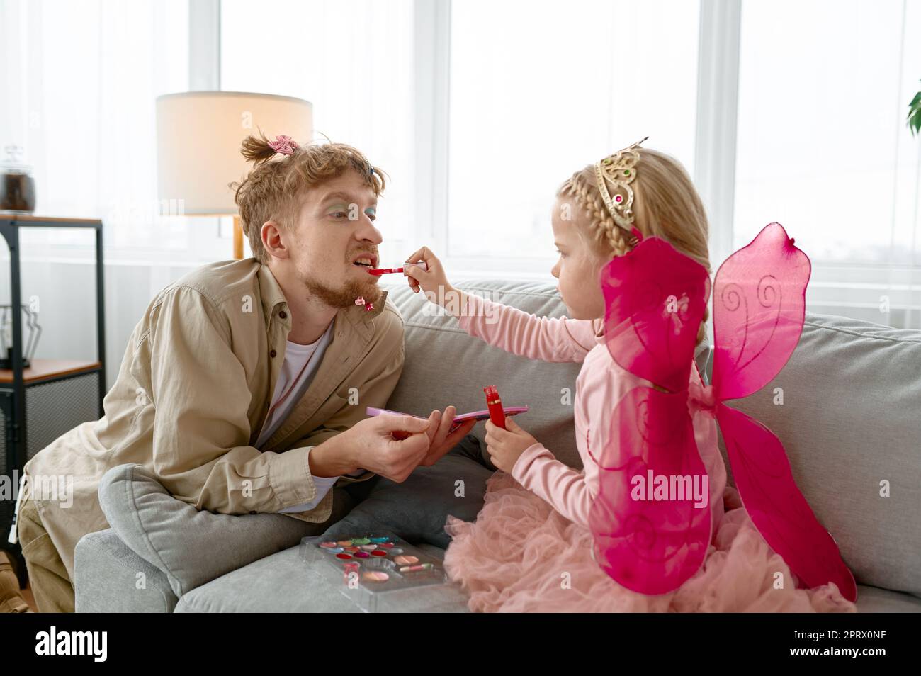 Little daughter putting lipstick on dads lips Stock Photo