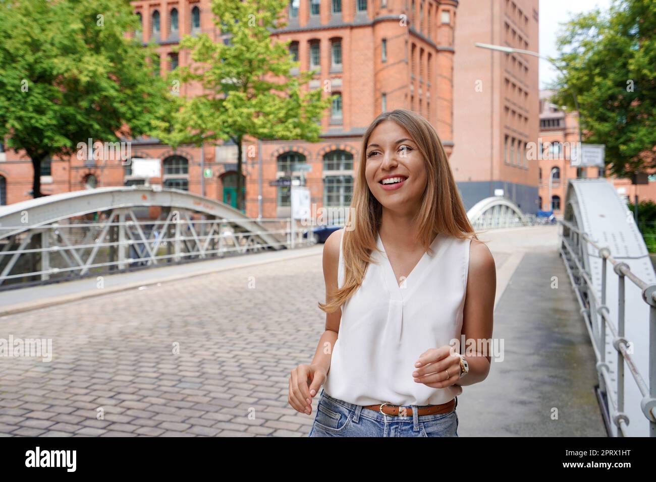 Beautiful cheerful young woman walking and smiling in Hamburg, Germany Stock Photo