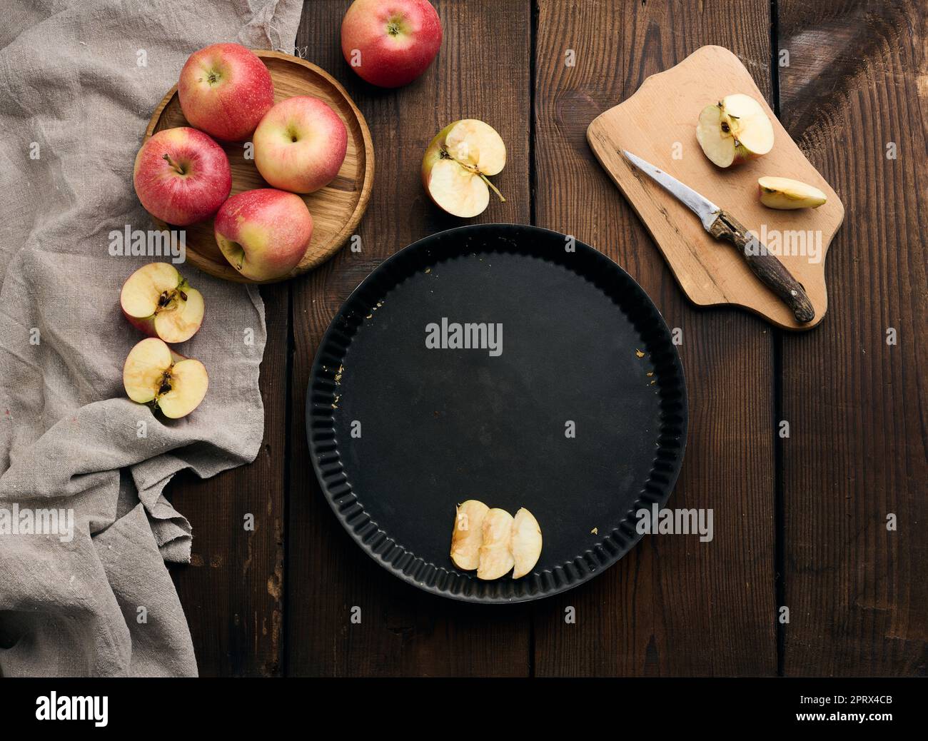 Empty round non-stick baking sheet, fresh apples on a wooden brown table Stock Photo