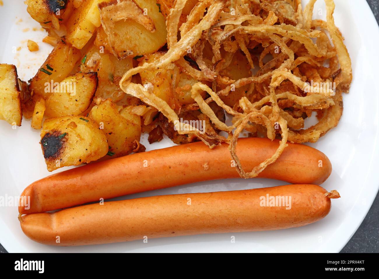 Close up portion of sausages with roasted potato Stock Photo