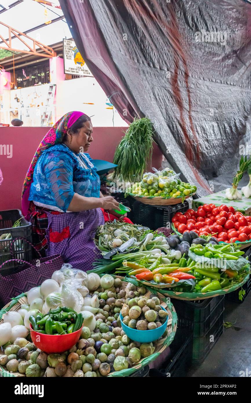 An indigenous Zapotec woman in traditional dress selling fresh produce in the market in