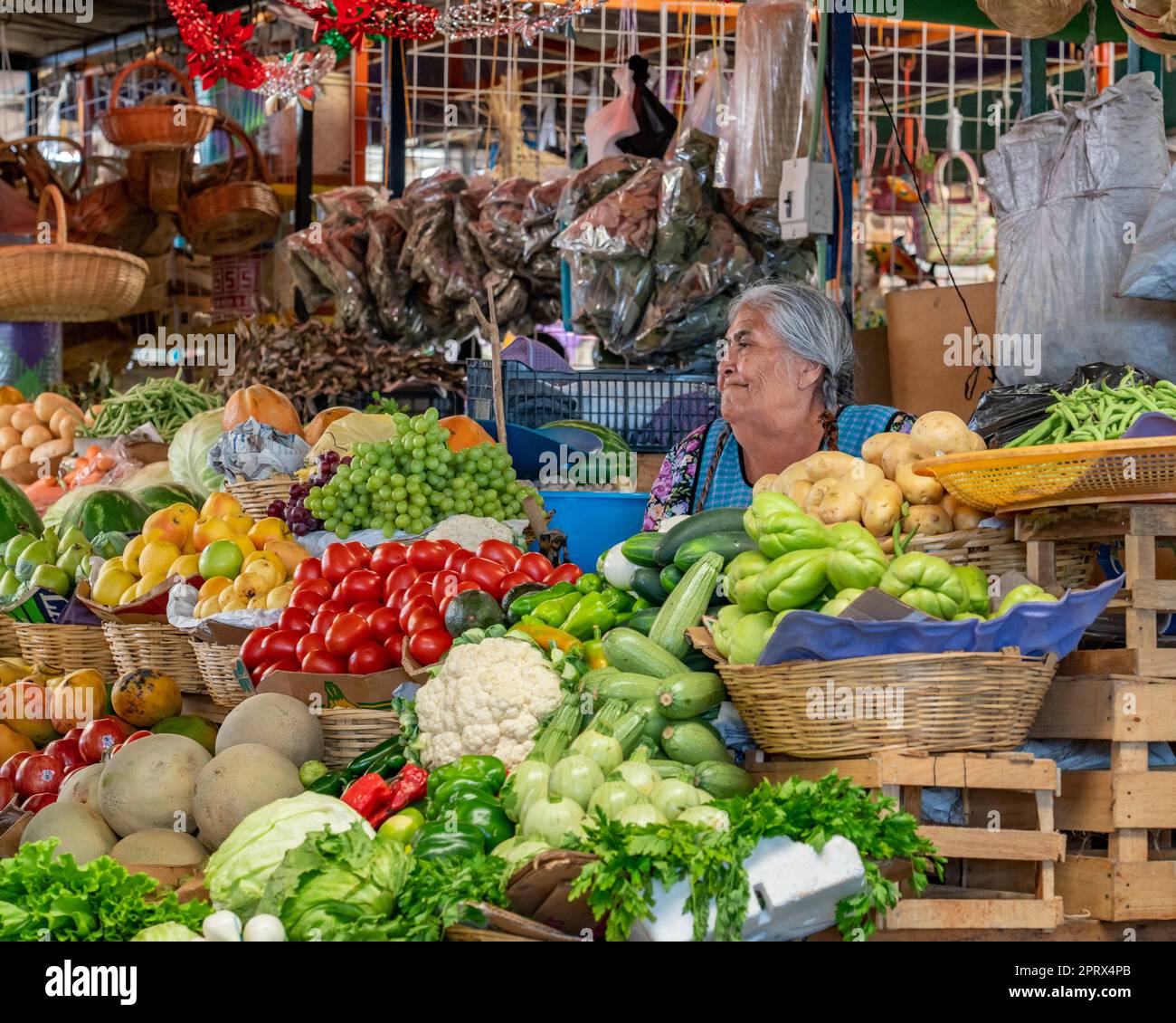 An indigenous Zapotec woman in traditional dress selling fresh produce in the market in Villa de