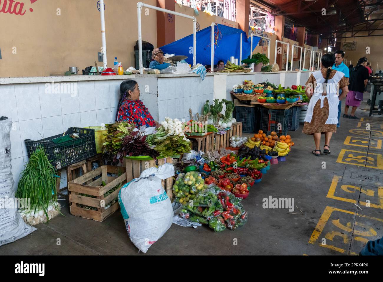 An indigenous Zapotec woman in traditional dress selling fresh produce in the market in