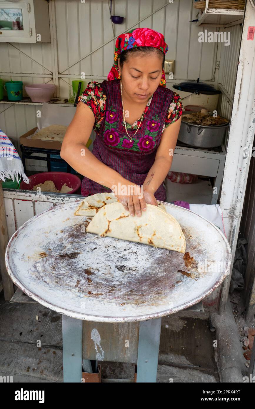 A young indigenous Zapotec woman makes yellow mole empanadas on a comal griddle in Tlacolula de Matamoros, Oaxaca, Mexico. Stock Photo