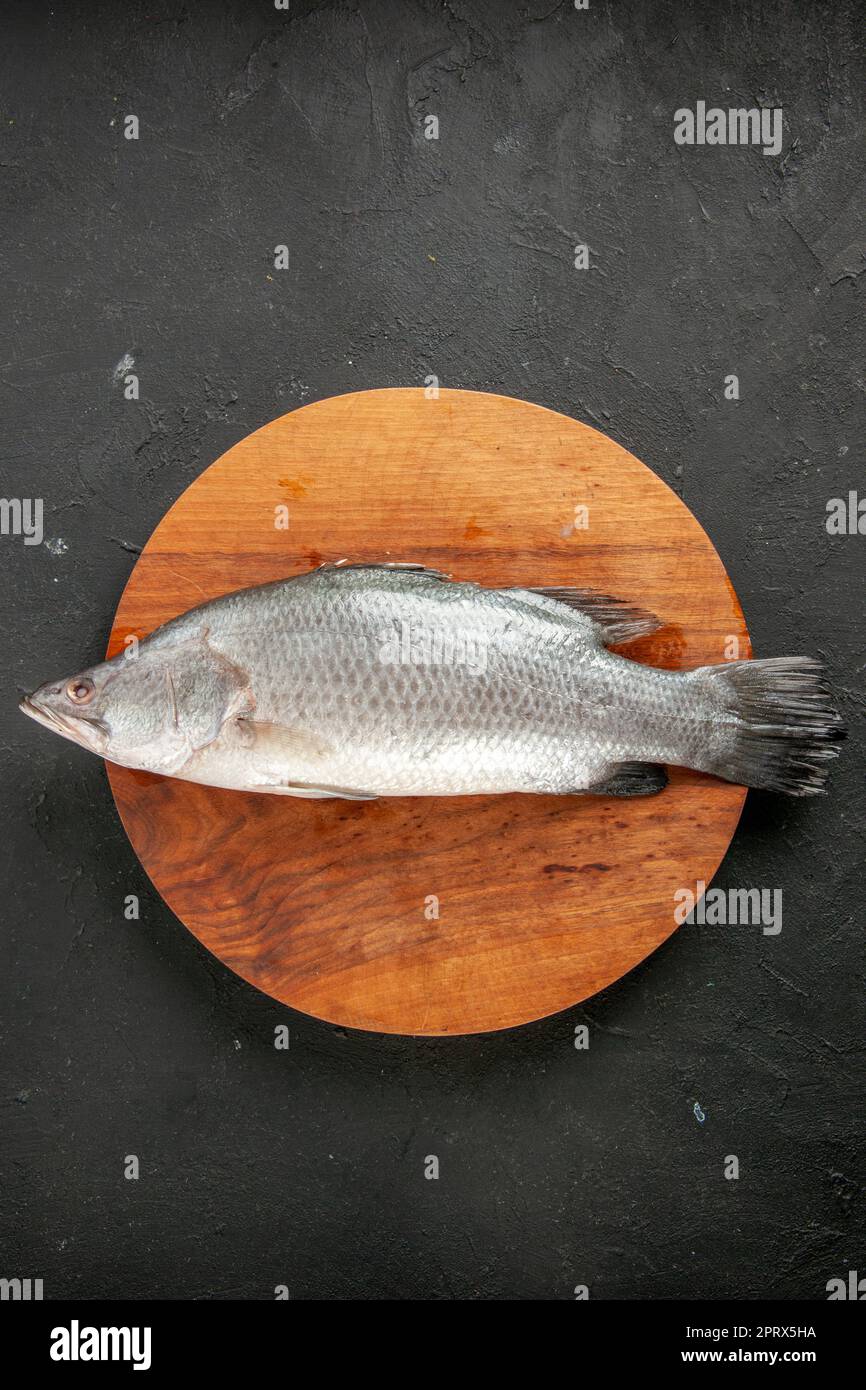 top view fresh raw fish on round wood board on black table with copy