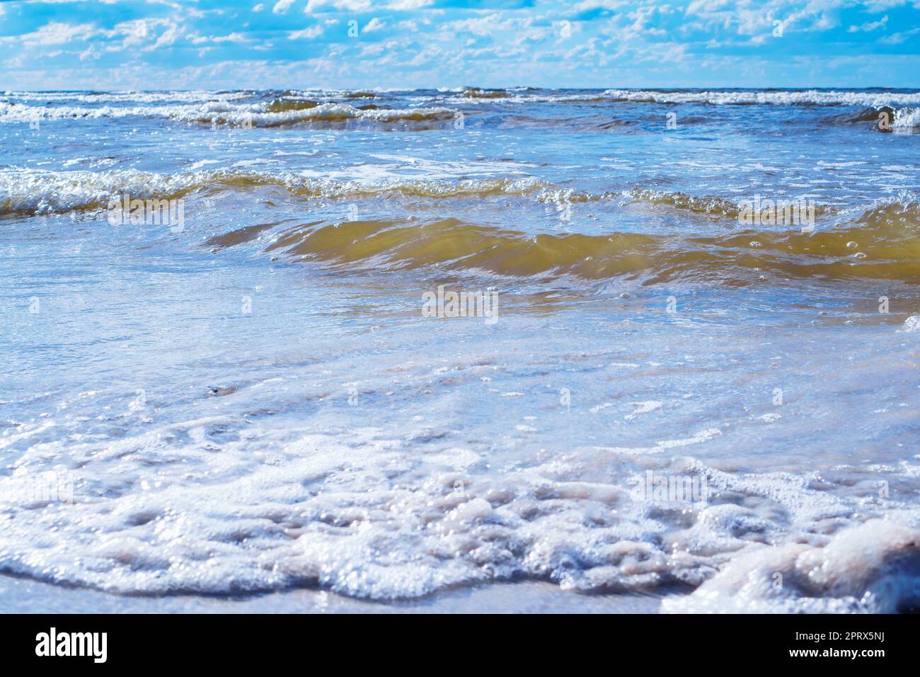 Bright blue sky with white clouds almost merges with sea waves with ...