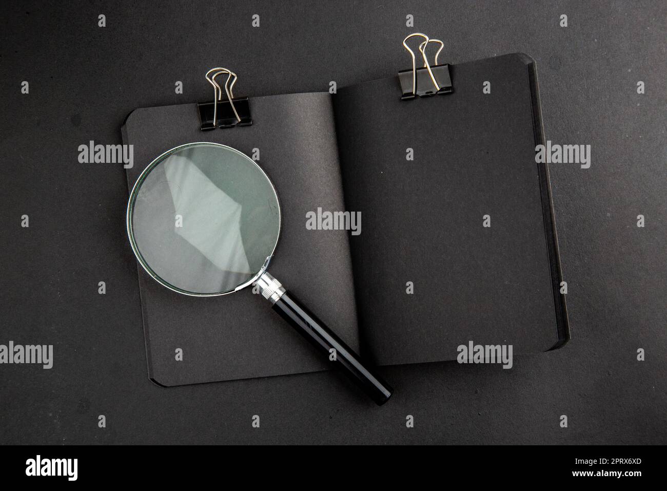 top view lack notepad binder clip lupa on black background Stock Photo