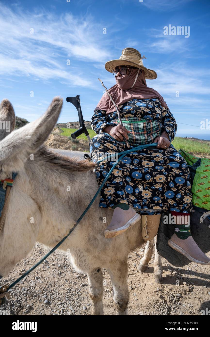 Woman with a straw hat and crutches riding a mule Stock Photo - Alamy