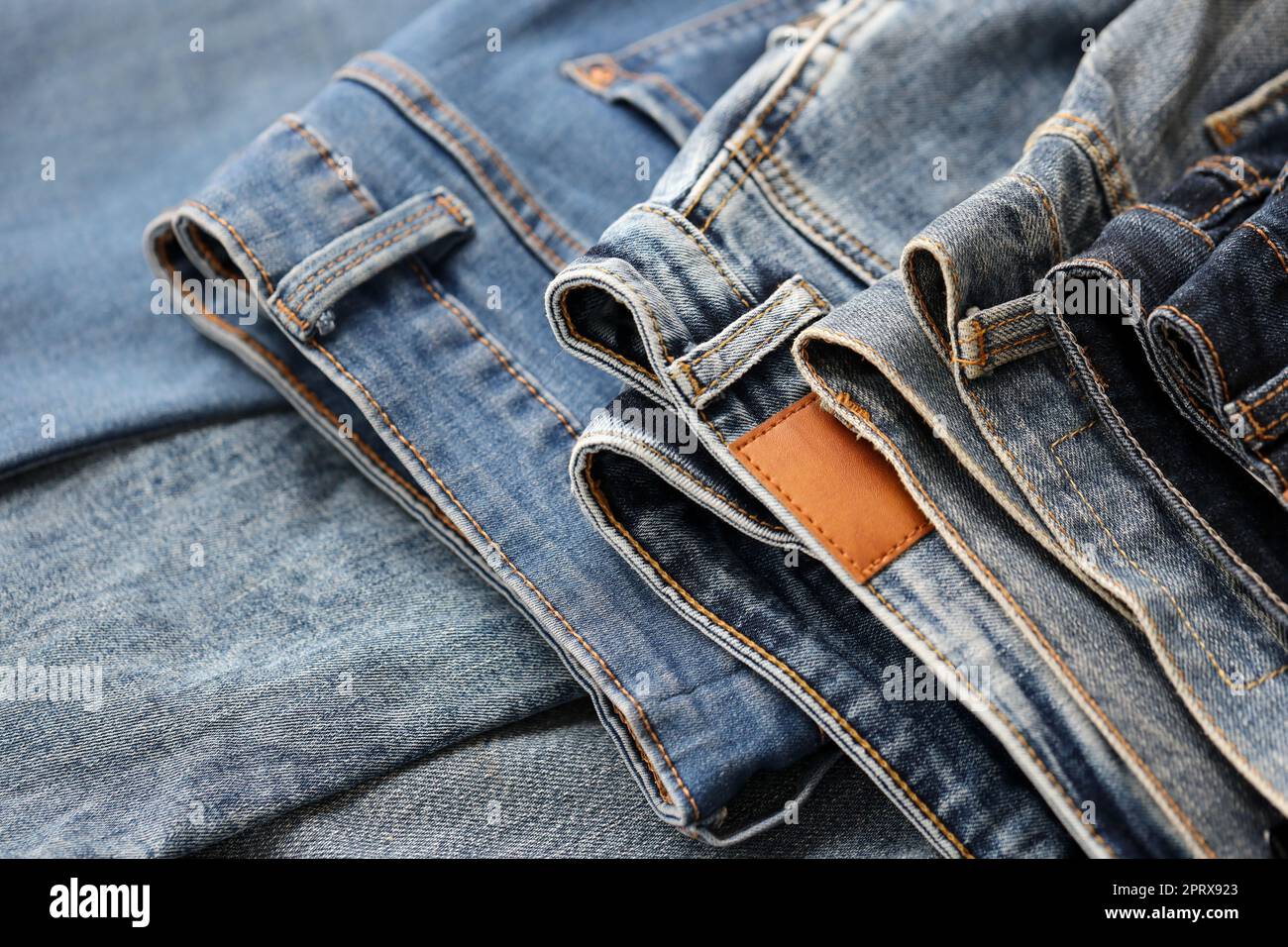 Many jeans in stack in wardrobe room. Row of pants denim jeans in