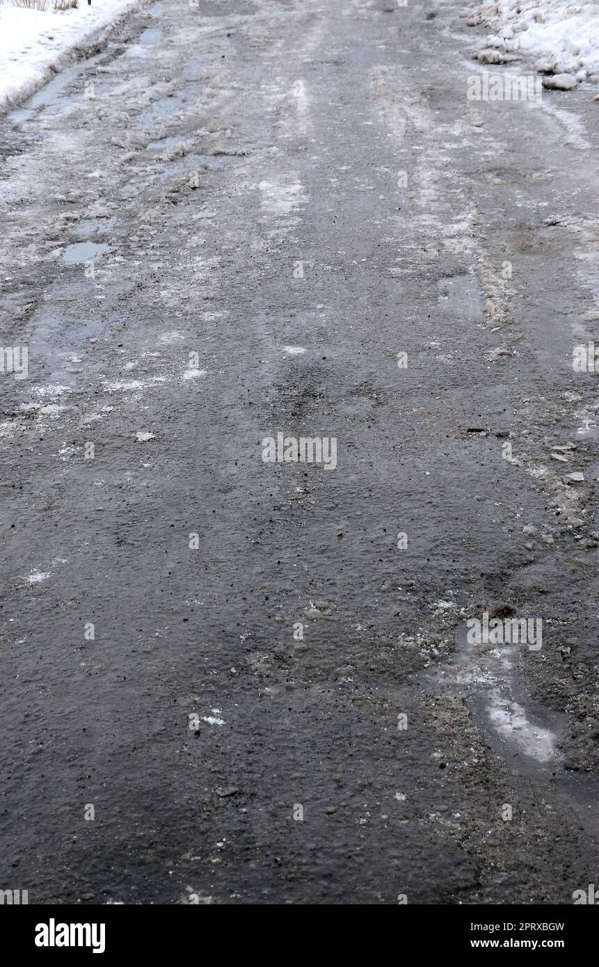 Damaged asphalt road with potholes caused by freezing and thawing ...
