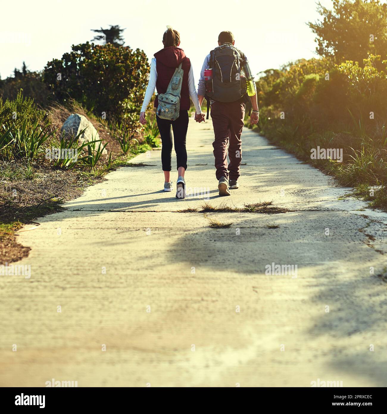Not all who wander are lost. Rearview shot of a young couple holding hands while walking along a hiking path Stock Photo