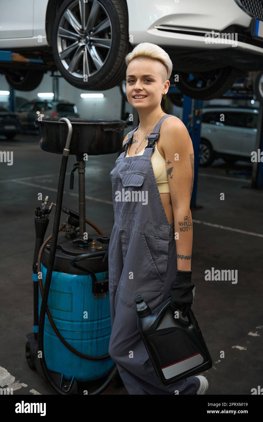 Smiling car mechanic stands with a device for draining oil Stock Photo