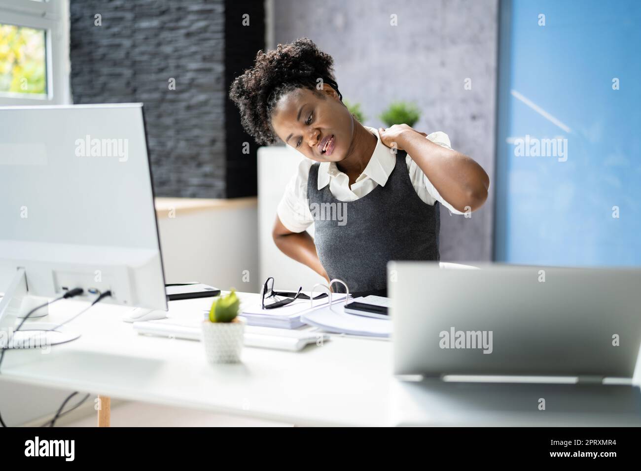 African Woman Sitting In Office Chair With Back Pain Stock Photo - Alamy