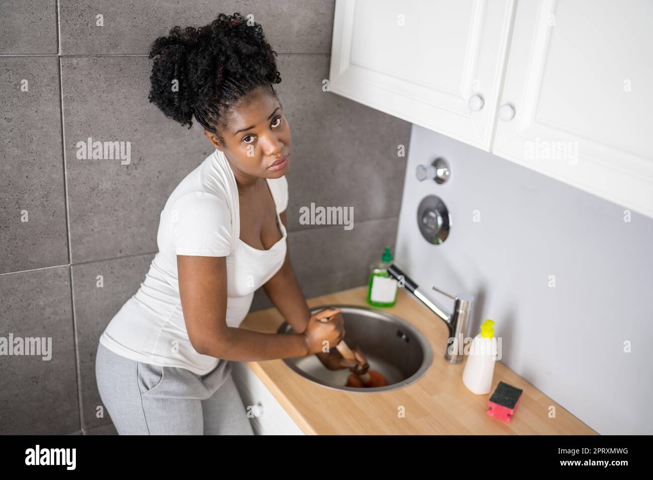 Cleaning Blocked Sink And Drain In Kitchen Using Plunger Stock Photo