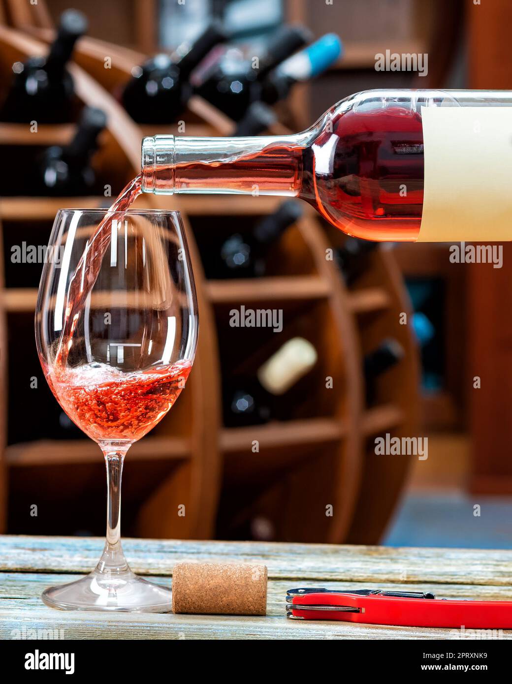 Winery. Pouring rose wine from the bottle into the wine glass for tasting, on a rustic wooden